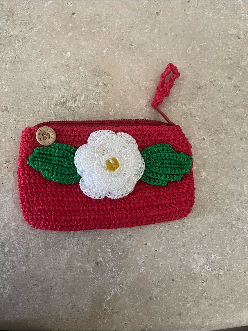 Hand Crafted red crochet wristlet with white flower and green leaves
